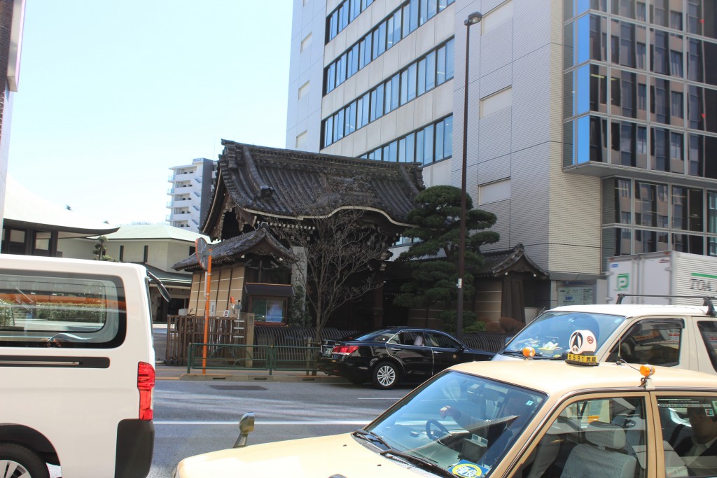 There are some traditional structures sandwiched between the modern buildings of Tokyo.
